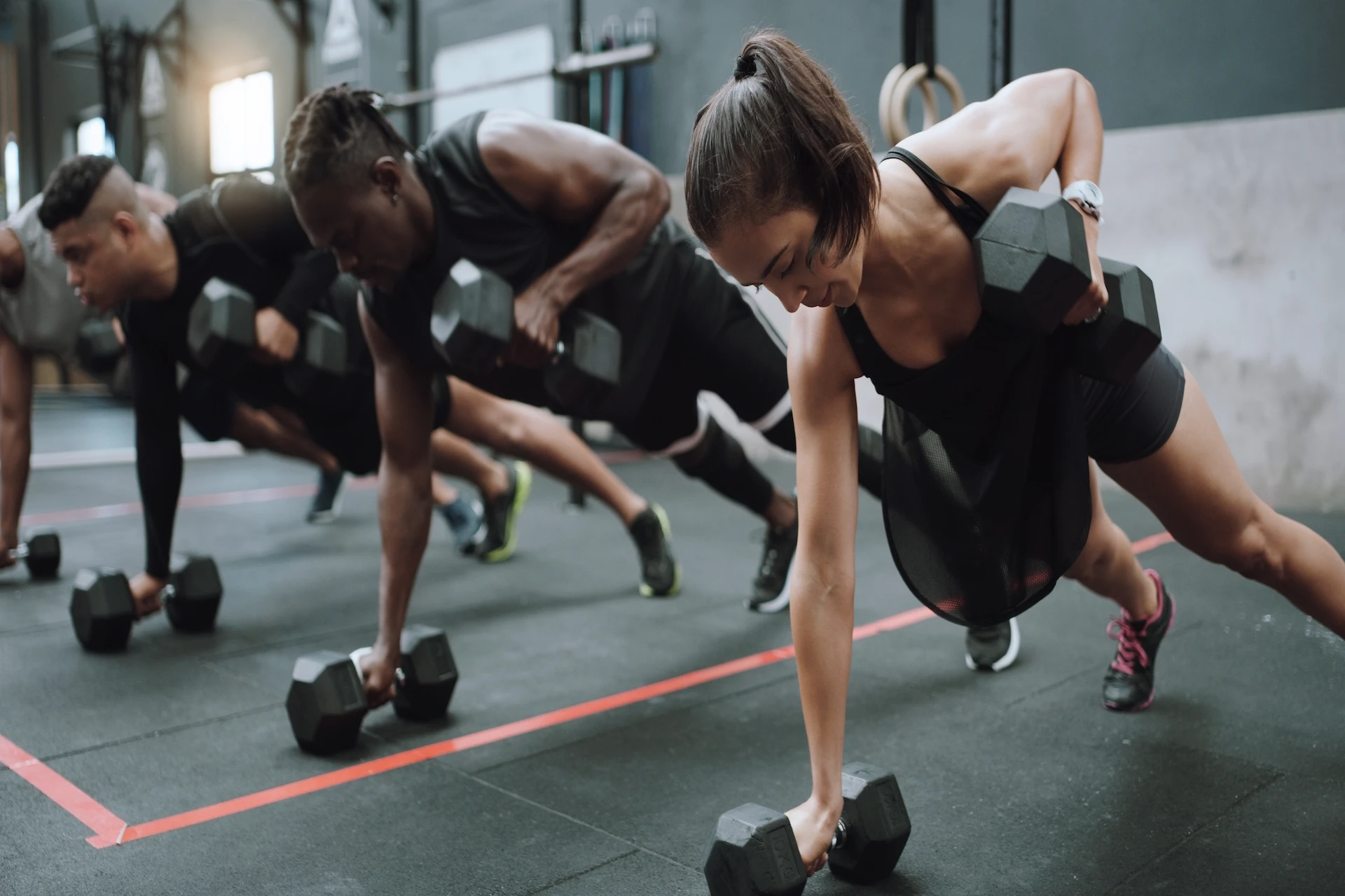 Members performing dumbbell plank rows in a group fitness class at Evolve Vegas to build strength and achieve fast body transformation results.